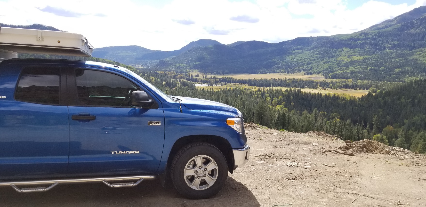 A blue car parked in front of a mountain

Description automatically generated