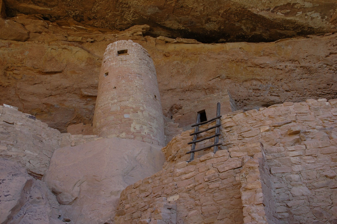 A close up of a stone building that has a rocky cliff

Description automatically generated