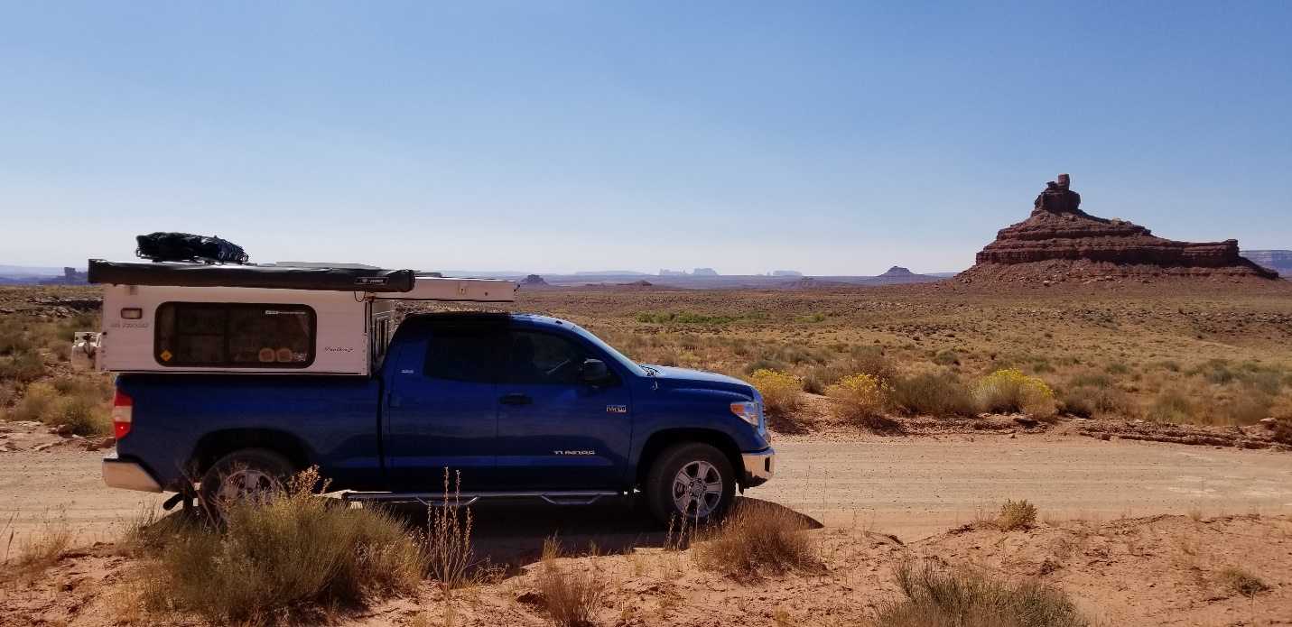 A truck is parked on the side of a dirt field

Description automatically generated