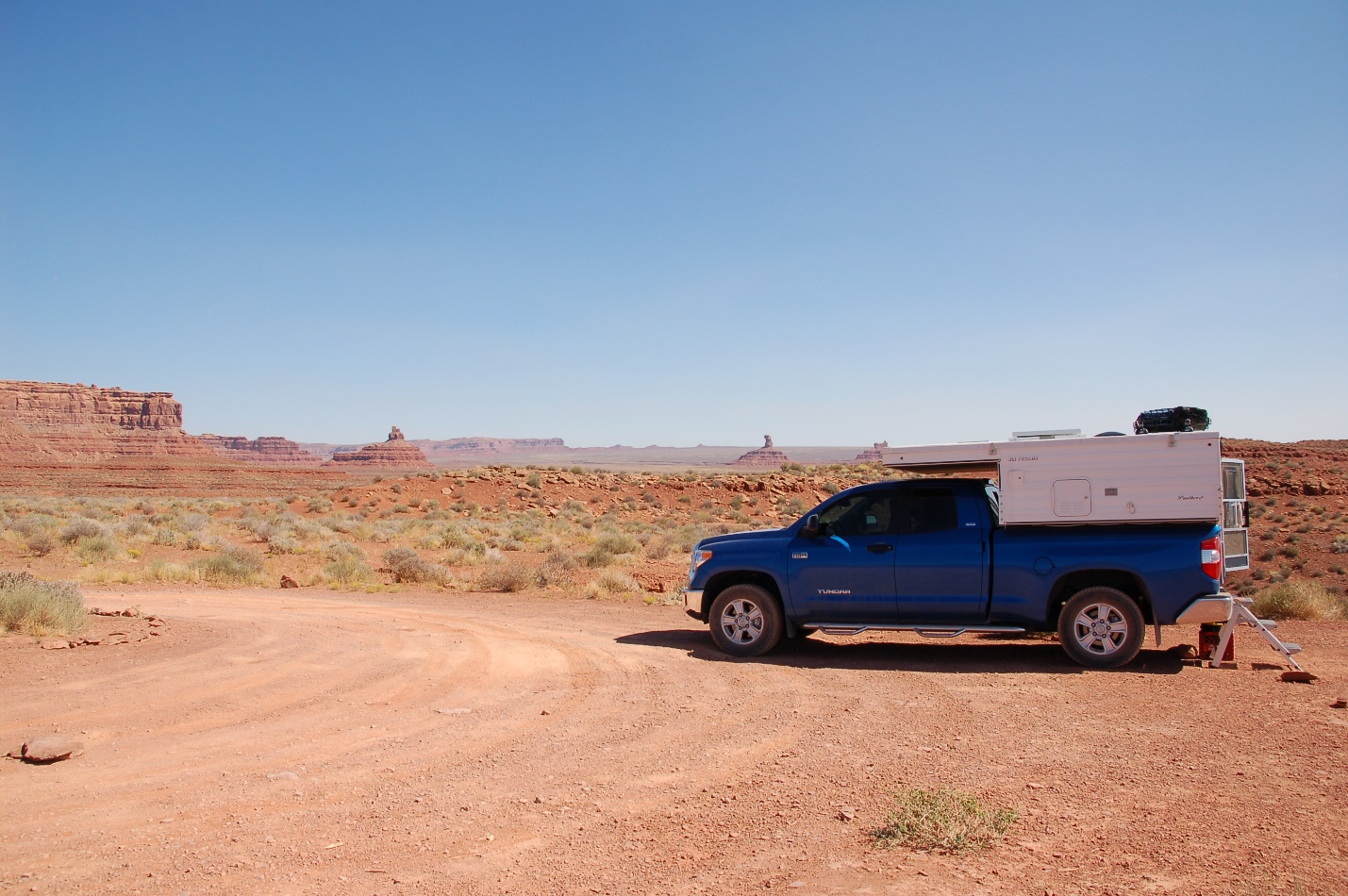 A truck parked on the side of a dirt road

Description automatically generated